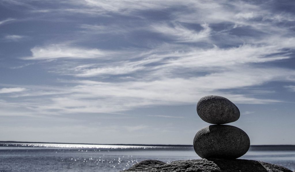 Як боротися зі стресом: прості техніки для спокою Tranquil seashore scene featuring stacked stones against an ocean backdrop, symbolizing balance.