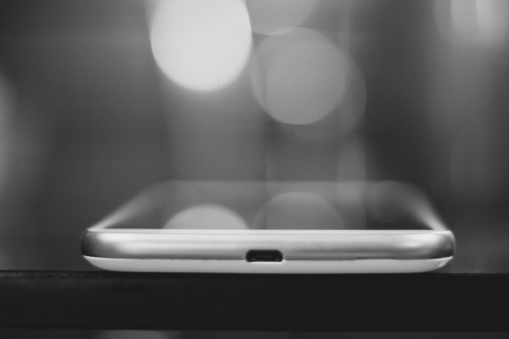 Як обрати смартфон у 2026 році: покрокова інструкція A sleek smartphone captured in a black and white bokeh setting, showcasing minimalist design.
