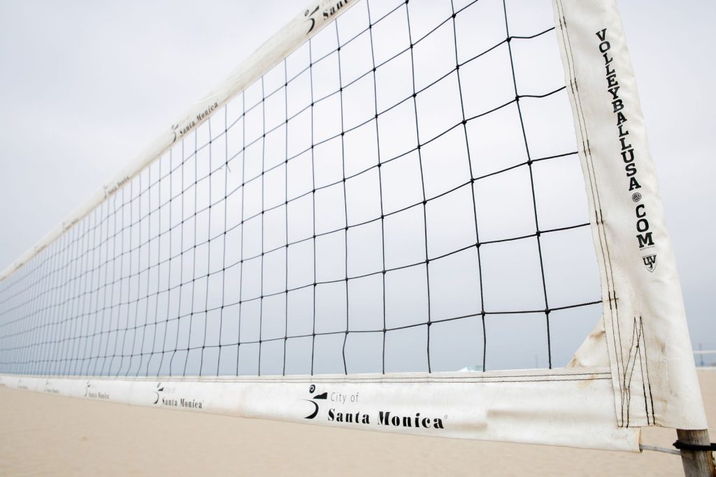 Правила волейболу: гайд для тих, хто починає Close-up of a volleyball net on Santa Monica beach, ideal for sports themes.