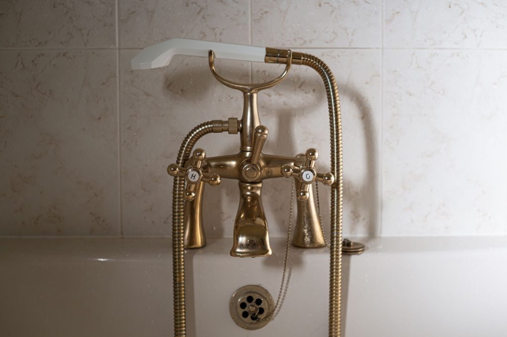 Загартовування організму: з чого почати новачку Close-up of a classic brass bathtub faucet with a ceramic hand shower in Greystoke, England.