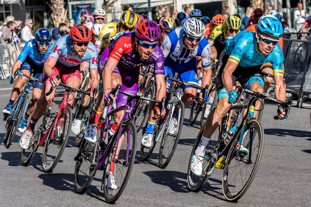 Велоспорт для початківців: з чого почати їзду Competitive cyclists in vibrant gear race through Alicante streets, showcasing speed and athleticism.