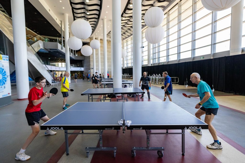 Настільний теніс: правила гри та основи для новачка Exciting table tennis game in a modern indoor venue. Players engaged under bright lighting and stylish decor.