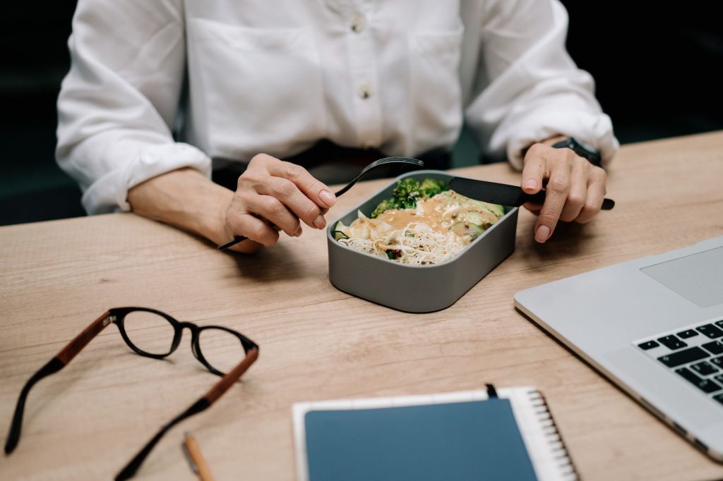 Харчування при сидячій роботі: практичні поради Adult enjoying a healthy meal at the office desk during lunch break.