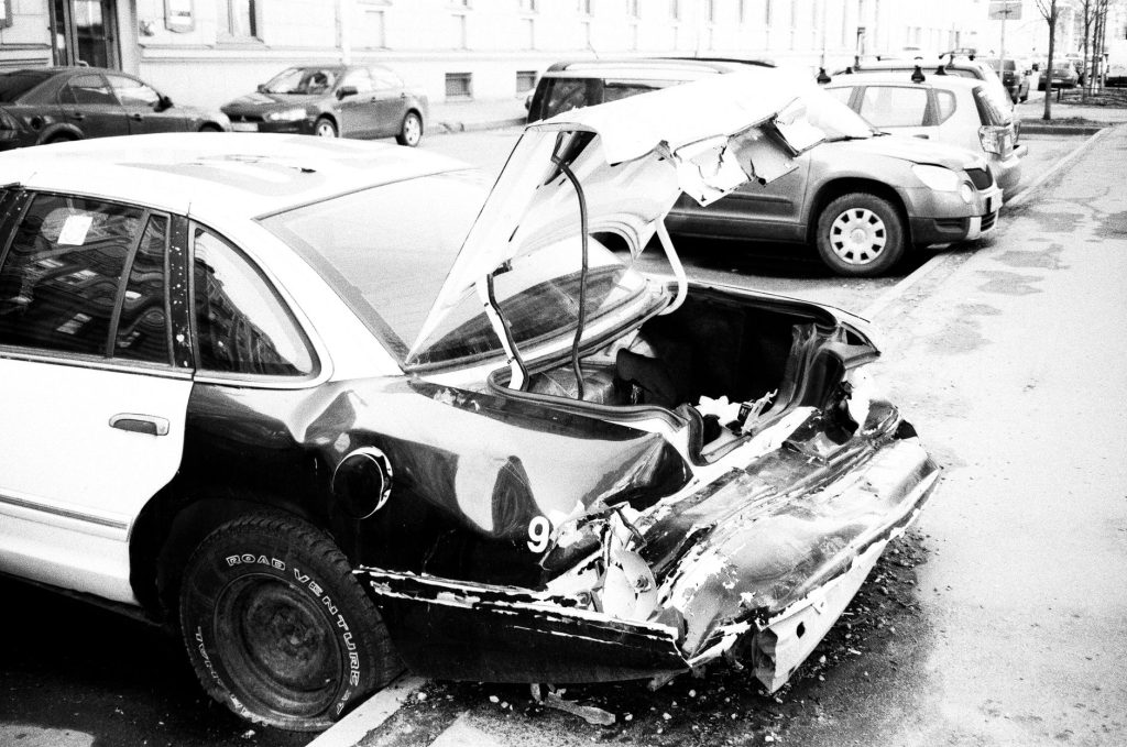 Що возити в багажнику: обов`язковий набір для водія A black and white photo of a wrecked car on an urban street, highlighting vehicle damage.