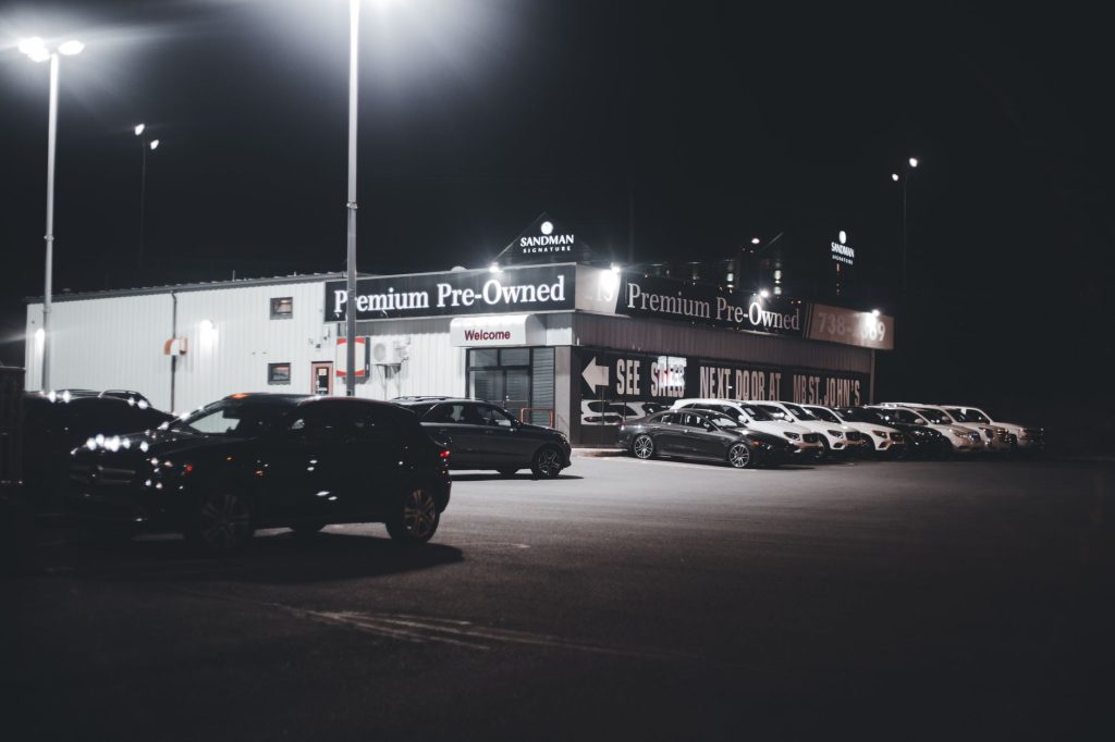Як обрати вживане авто: покрокова інструкція для водія Illuminated car dealership lot showcasing premium pre-owned vehicles at night.