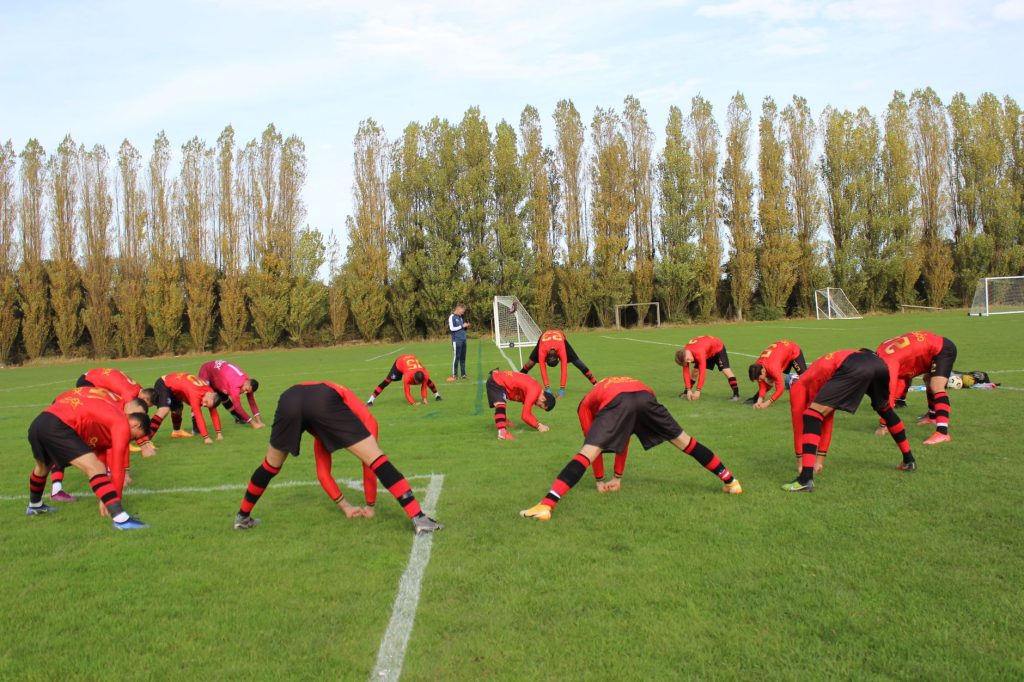 Розминка перед силовим тренуванням: навіщо потрібна Soccer team stretching on the field before a game on a clear day, preparation for the match.