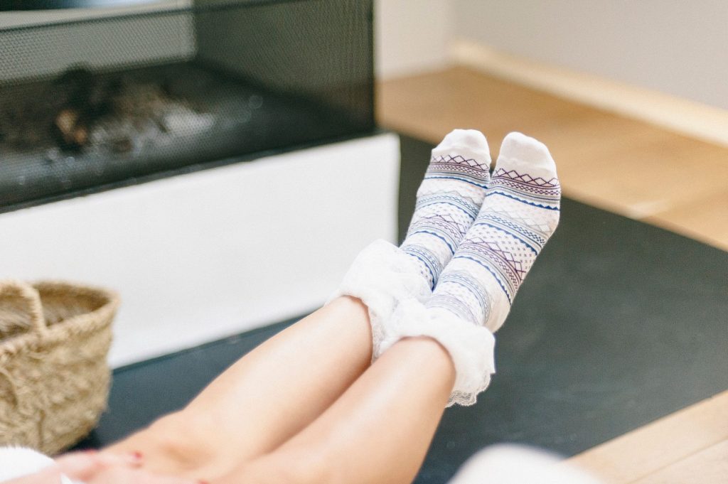 Підготовка дому до зими: чек-лист для затишку й економії Relaxing indoors with warm patterned socks in front of a cozy fireplace. Ideal for winter lifestyle imagery.