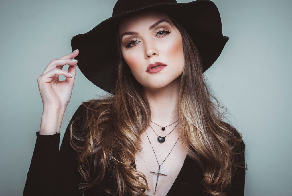 Stylish portrait of a young woman wearing a black hat and jewelry, highlighting elegance and fashion.