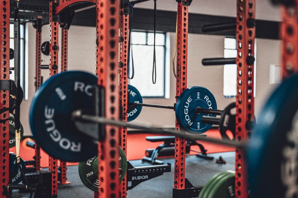 Присідання зі штангою: техніка, помилки та прогрес Close-up view of gym equipment with barbells and weight plates, perfect for strength training enthusiasts.