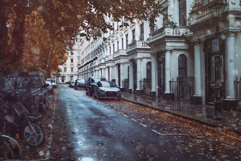 A picturesque London street with parked cars and classic architecture on a rainy autumn day.