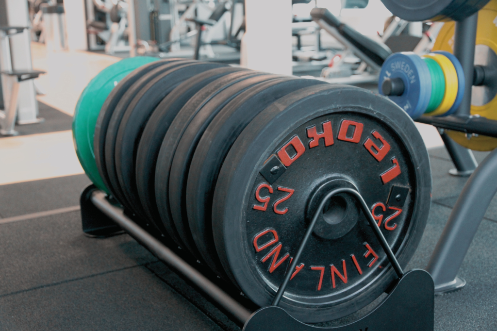 Прогресія навантаження: як стабільно рости в силі Close-up of stacked weight plates in a modern gym setting.