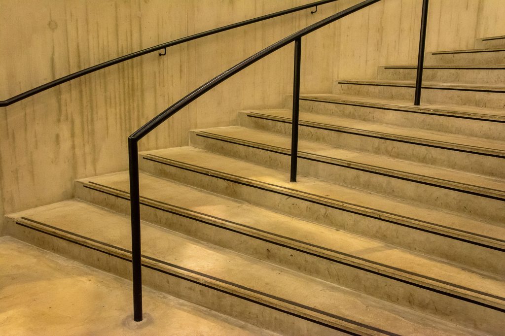 Close-up of a modern concrete staircase featuring sleek black railings in an indoor setting.