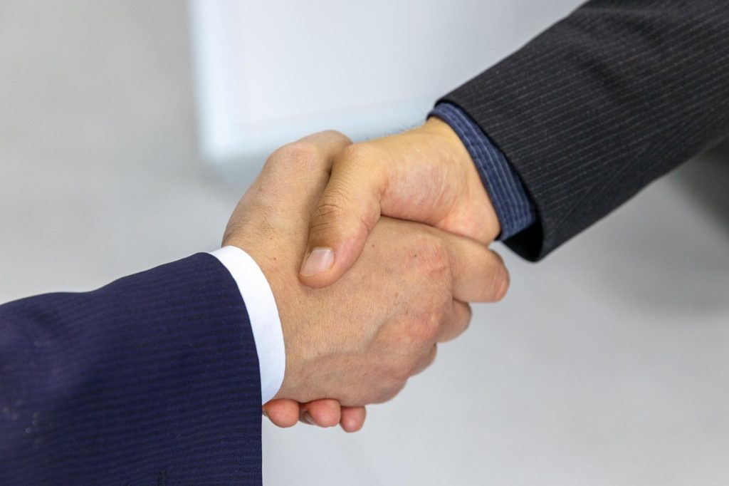 Як знайти першого клієнта: покроковий план Close-up of two businessmen shaking hands, symbolizing agreement and partnership.
