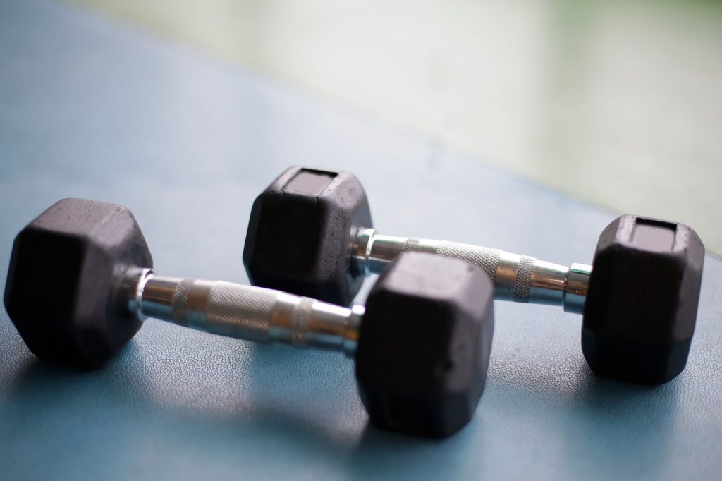 Close-up view of two black hex dumbbells on a gym floor, perfect for fitness content.