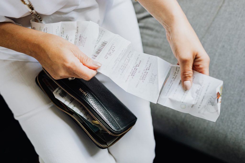 Права споживача: як повернути неякісний товар у магазин Close-up of a woman's hands managing multiple receipts taken from a black wallet.