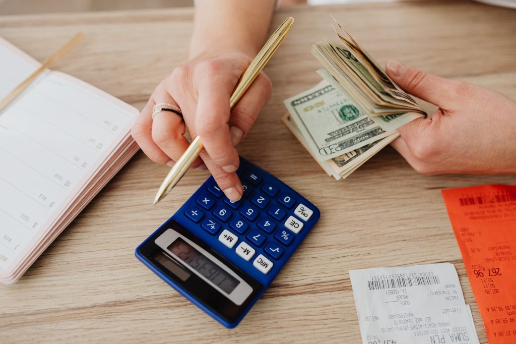 Основи особистих фінансів: як планувати бюджет з нуля Hands handling cash and calculator for budget planning. Modern financial scene.