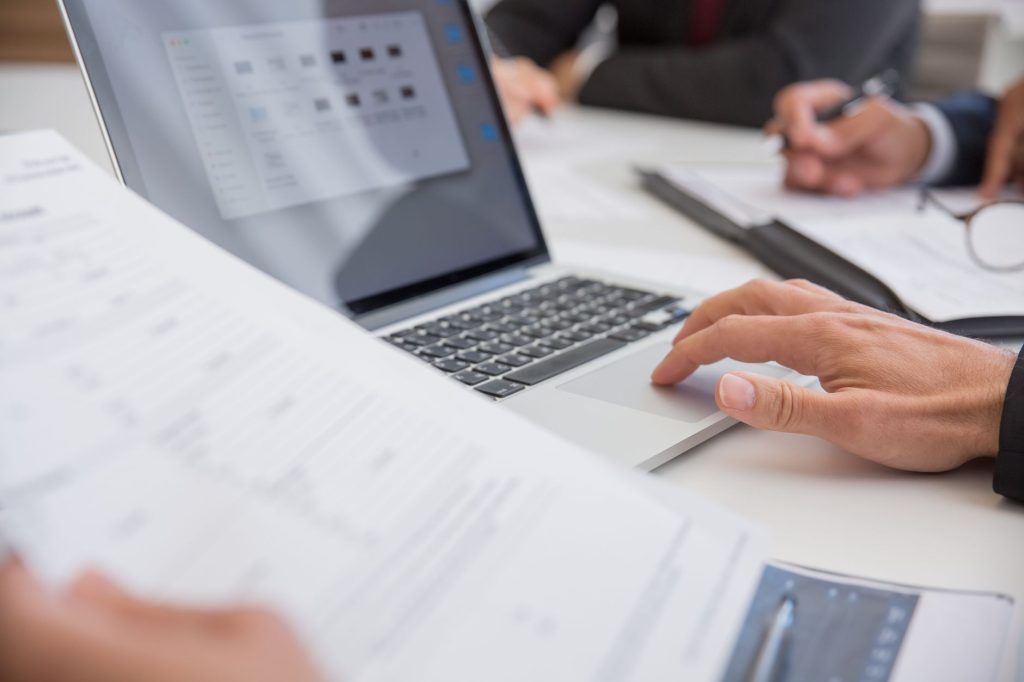 Як закрити ФОП онлайн через Дію: покрокова інструкція Close-up of hands working on documents and a laptop in an office setting, illustrating teamwork and productivity.