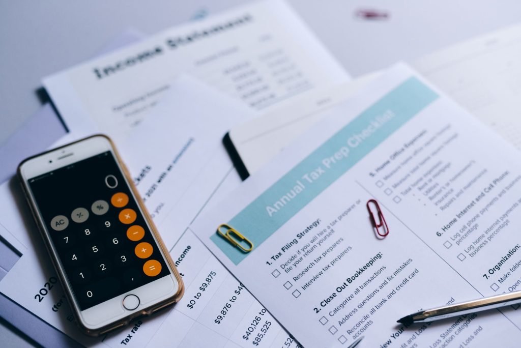 Податкова знижка: як повернути частину сплаченого податку Tax preparation setup with documents, smartphone calculator, and checklist.